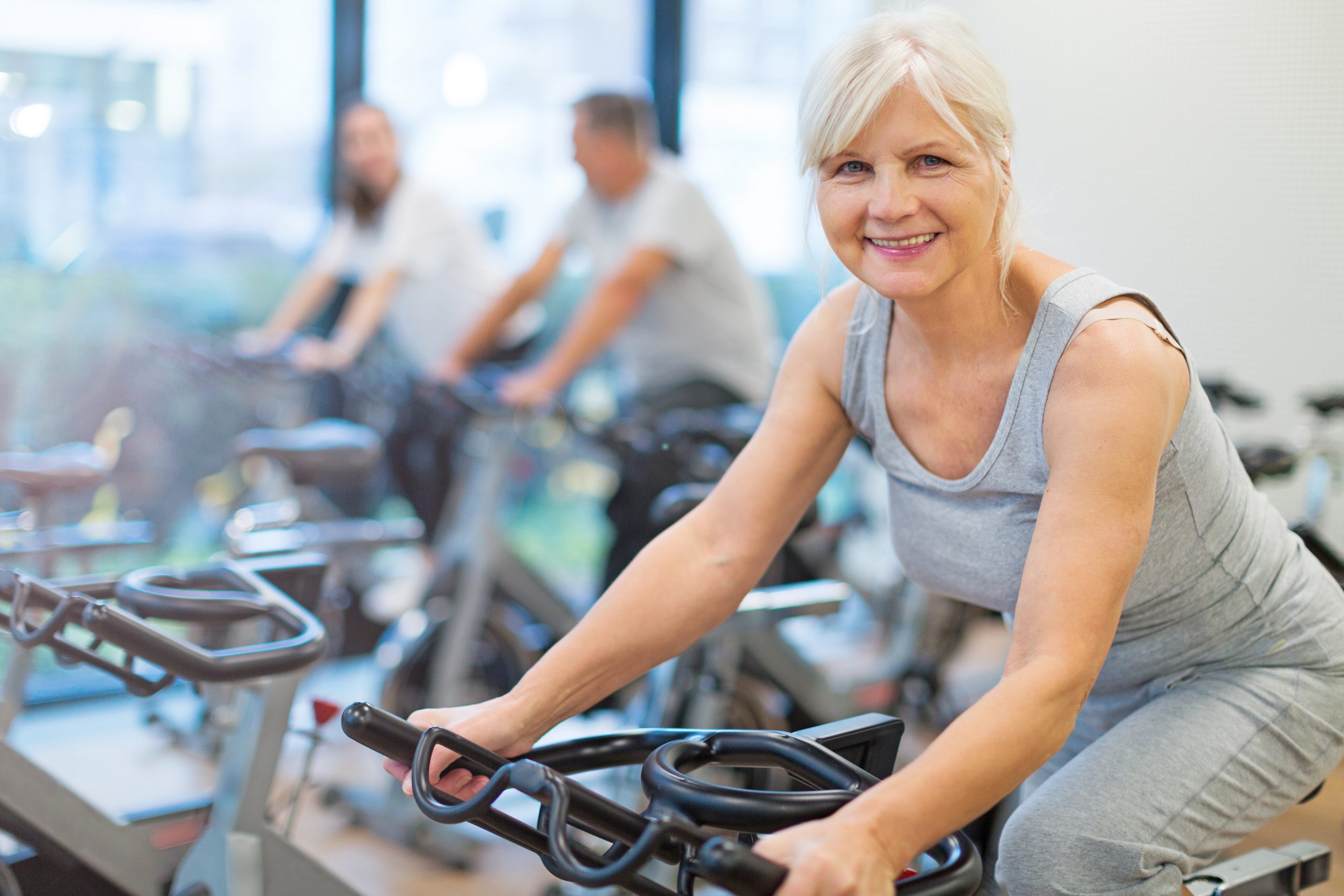 A woman riding an exercise bike in a gym.